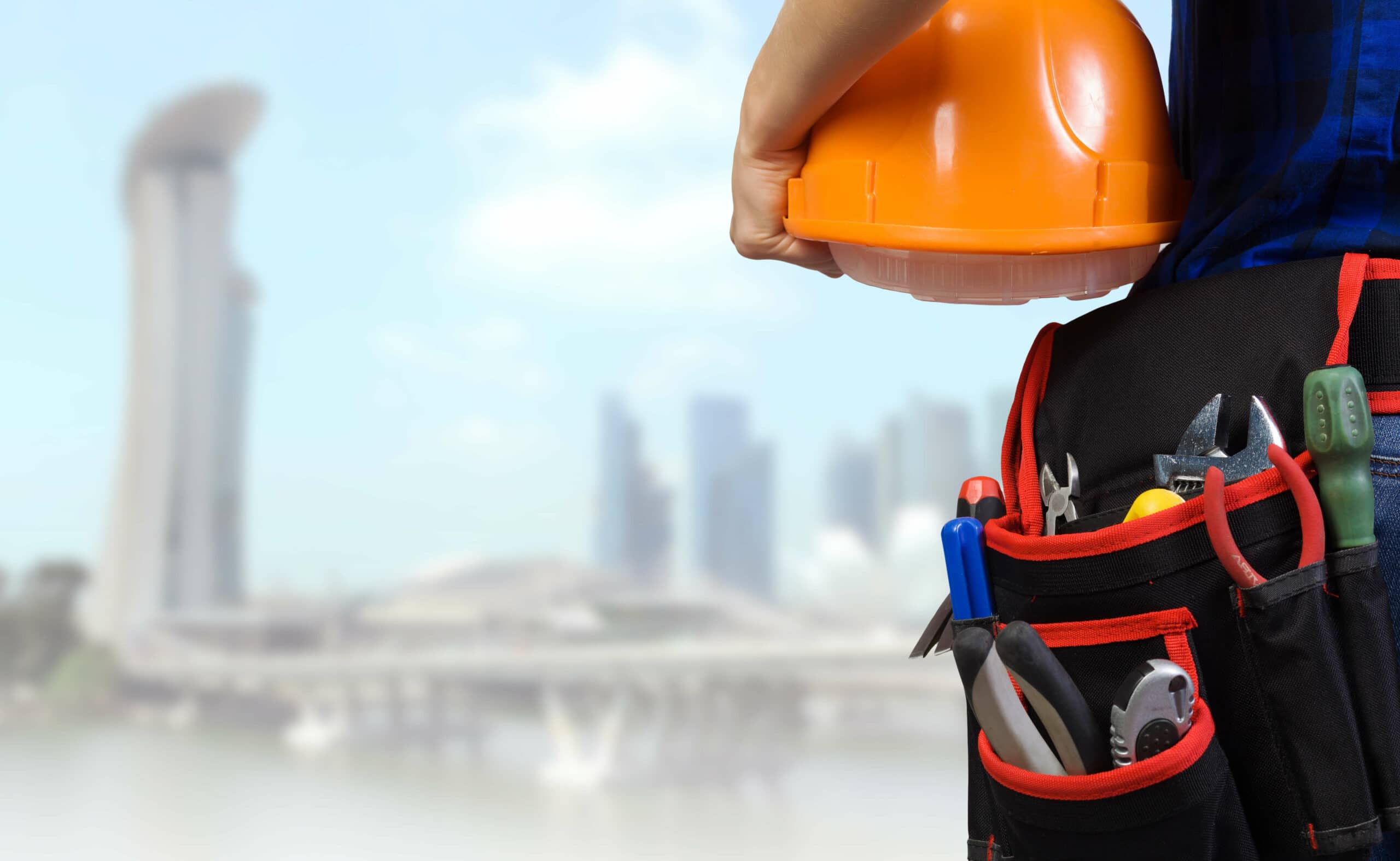 Close up of woman mechanic with yellow helmet in hand against city background