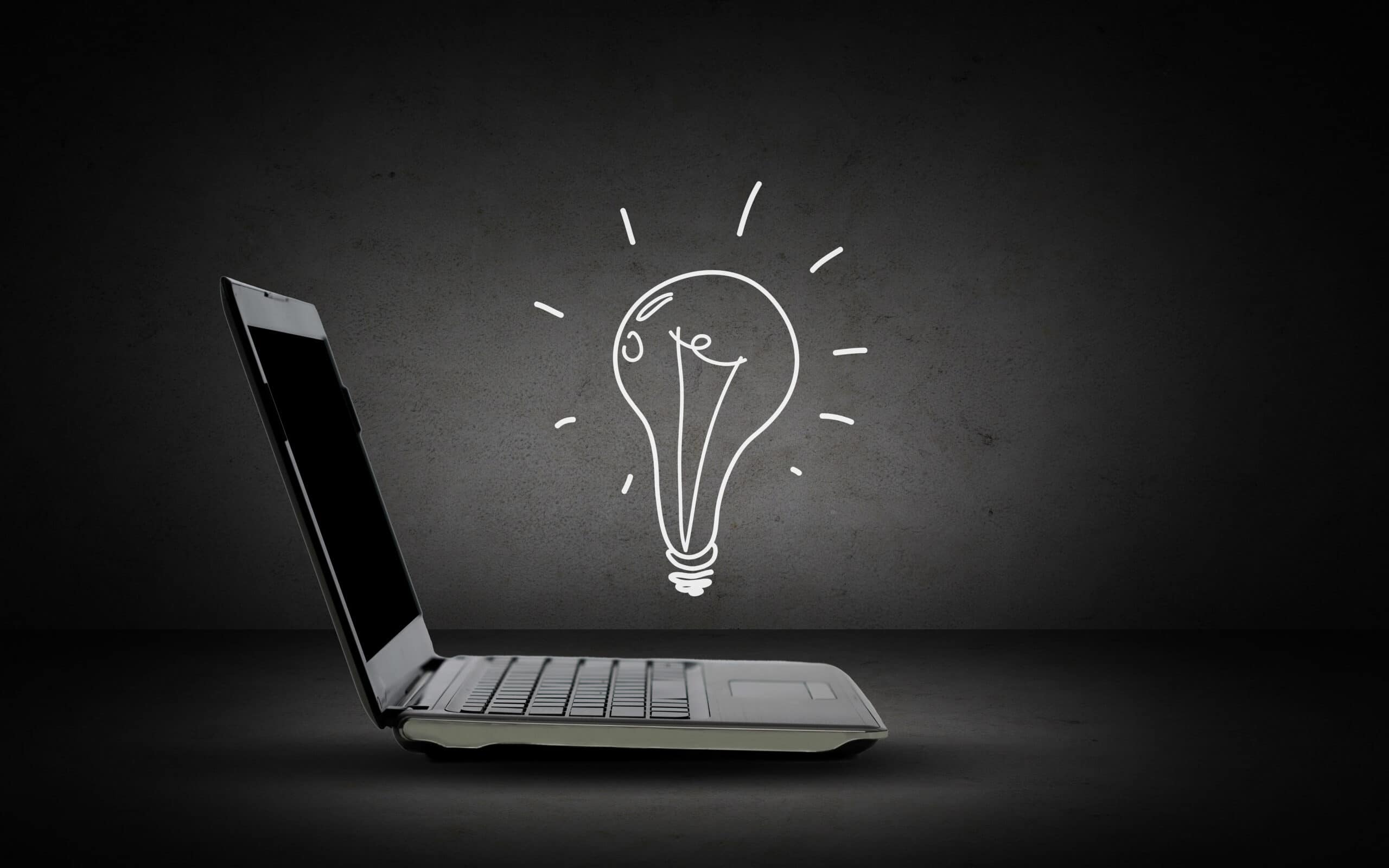 technology, business, start up and idea concept - open laptop computer with lighting bulb doodle over dark gray background